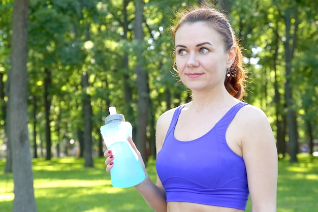 Jeune femme sportive de l'eau potable à partir d'une bouteille