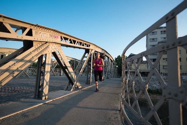 jeune femme sportive faisant du jogging sur le pont le matin ensoleillé de la ville