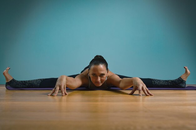 Photo une jeune femme sportive faisant des étirements debout une jeune fille mince pratiquant le yoga à l'intérieur sur un fond bleu