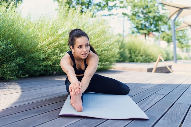 Photo une jeune femme sportive fait du yoga avec un tapis de yoga au concept de mode de vie actif en plein air du parc