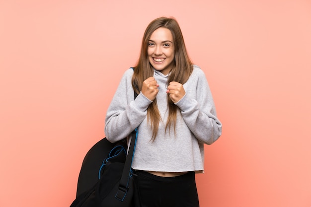 Jeune femme sportive sur fond rose isolé célébrant une victoire