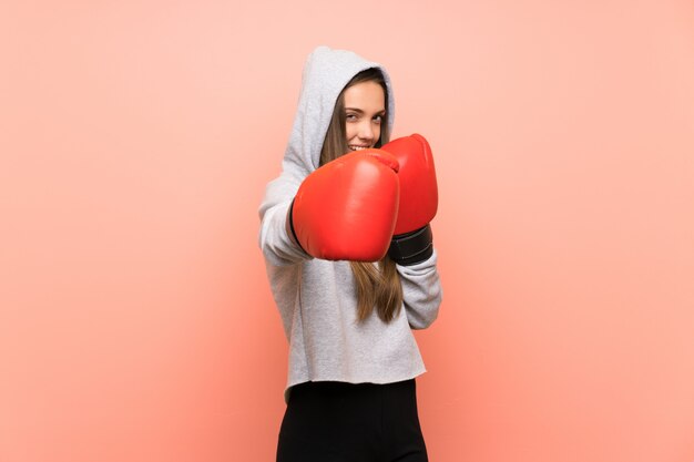 Jeune femme sportive sur fond rose isolé avec des gants de boxe