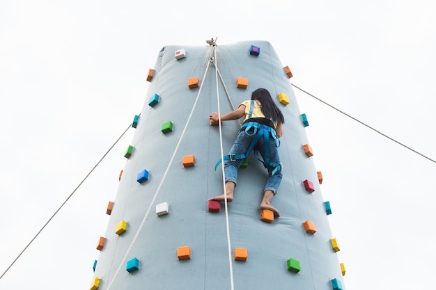 Jeune femme sportive grimper sur le mur de montage pratique en plein air, vue arrière