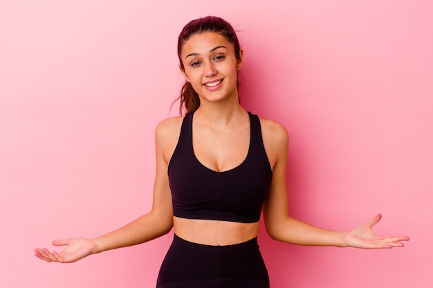 Jeune femme sportive isolée sur un mur rose montrant une expression de bienvenue