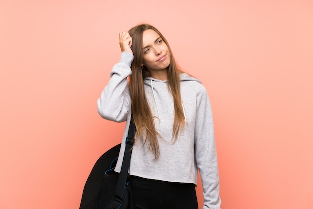 Jeune femme sportive isolée rose ayant des doutes et avec une expression du visage confuse