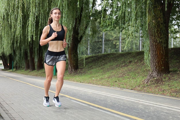 Jeune femme sportive jogging dans le parc.