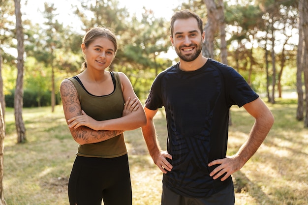 Jeune femme sportive joyeuse et heureuse et homme posant à l'extérieur dans un parc verdoyant