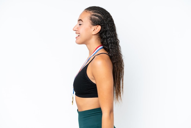 Jeune femme sportive avec des médailles isolées sur fond blanc en riant en position latérale