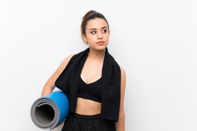 Jeune femme sportive sur un mur blanc avec tapis