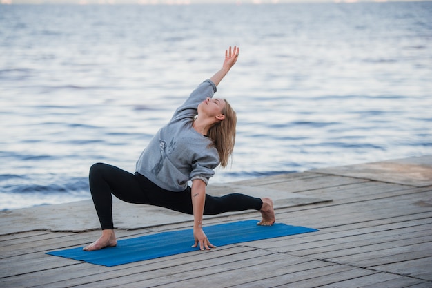 Jeune femme sportive pratiquant le yoga sur la plage