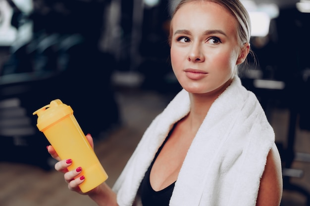 Jeune femme sportive prenant un verre dans une salle de sport après l'entraînement