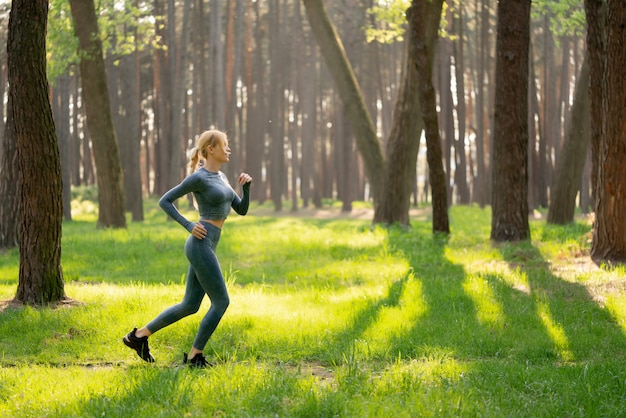 Jeune femme sportive qui court dans le parc verdoyant