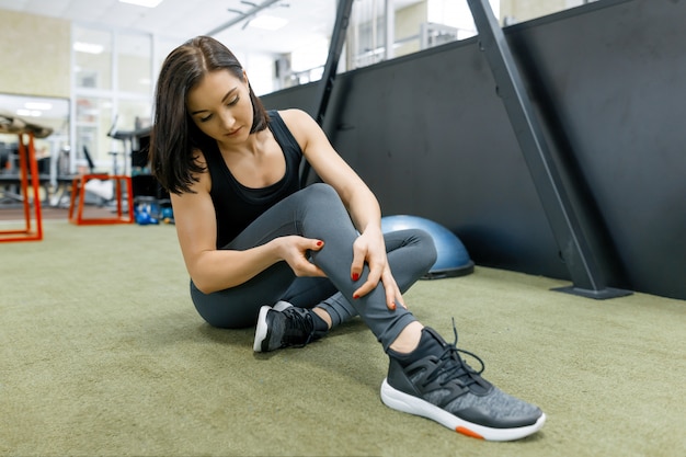 Jeune femme sportive reposant sur le sol après des exercices dans la salle de gym