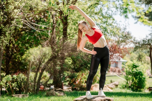 Jeune femme sportive s'échauffant à l'extérieur du parc