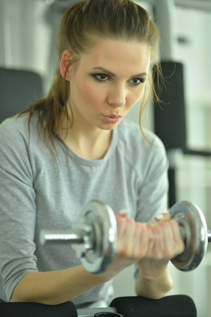 Jeune femme sportive s'entraînant avec haltère dans la salle de gym