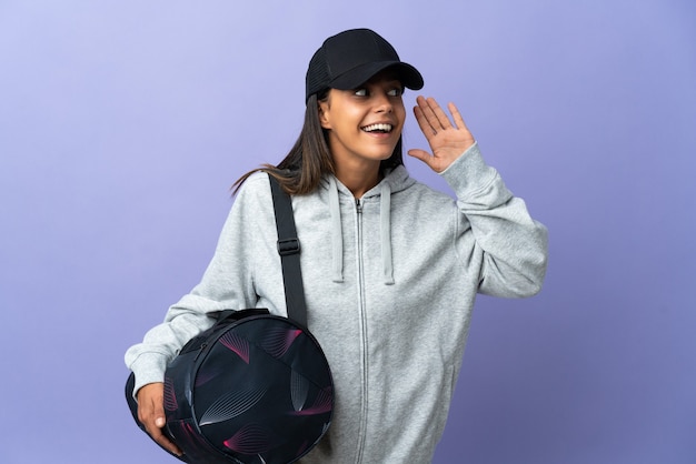 Photo jeune femme sportive avec sac de sport, écouter quelque chose en mettant la main sur l'oreille