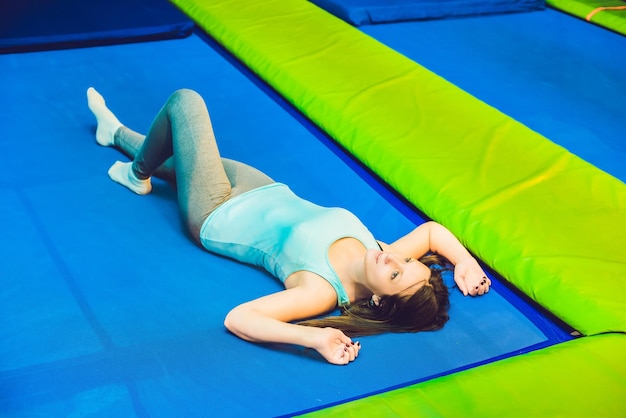 Jeune femme sportive sautant sur un trampoline dans un parc de remise en forme et faisant de l'exercice à l'intérieur