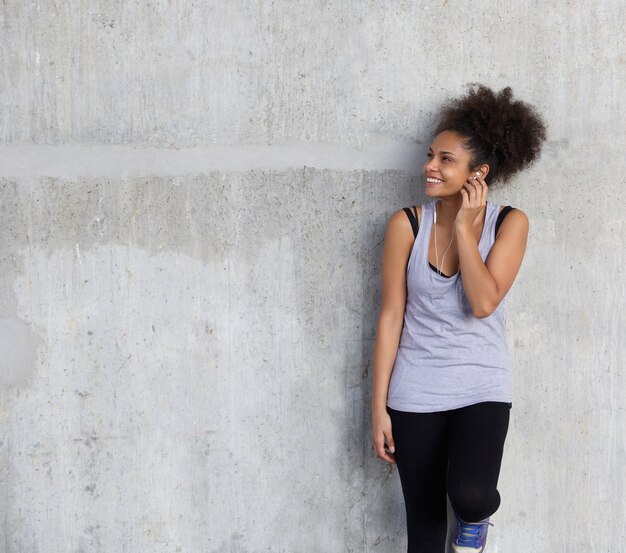 Jeune femme sportive, souriant avec des écouteurs