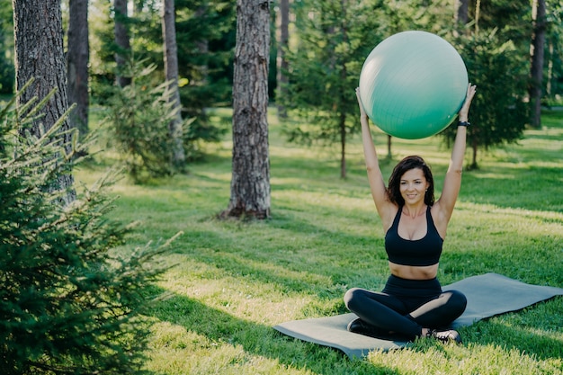 Jeune femme sportive travaillant à l'extérieur avec ballon