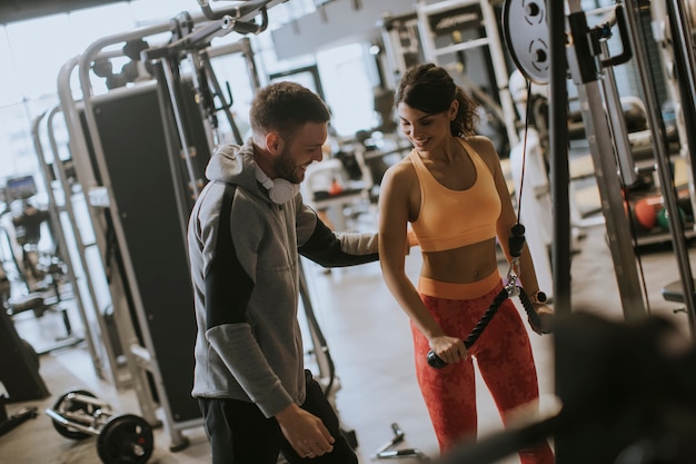 Photo jeune femme sportive travaillant sur une machine dans une salle de sport avec entraîneur personnel