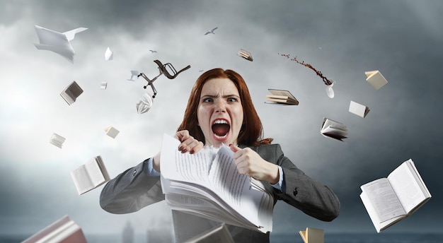Jeune femme stressée folle au travail, déchirant des documents avec une expression faciale frustrée. Technique mixte