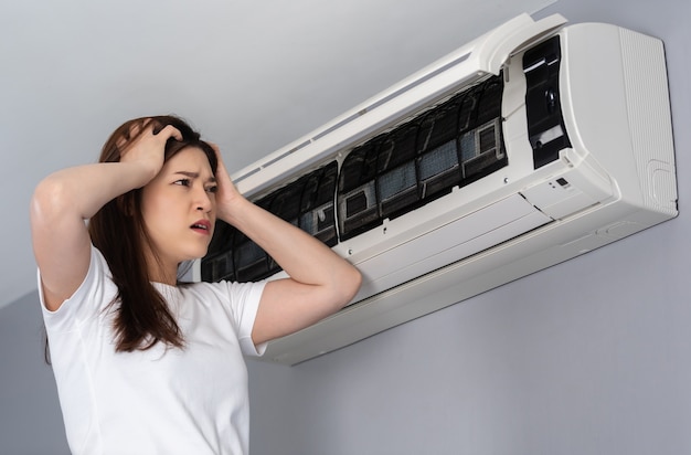 Une jeune femme stressée a un problème avec le climatiseur à la maison