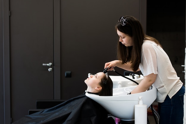 Jeune femme styliste sécher les cheveux de la femme avec de l'eau dans un salon de coiffure