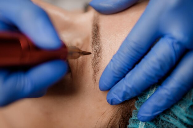 Jeune femme subissant une procédure de maquillage permanent des lèvres dans un salon de tatouage en gros plan