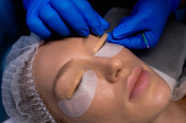 Jeune femme subissant une procédure de stratification des cils dans un salon de beauté