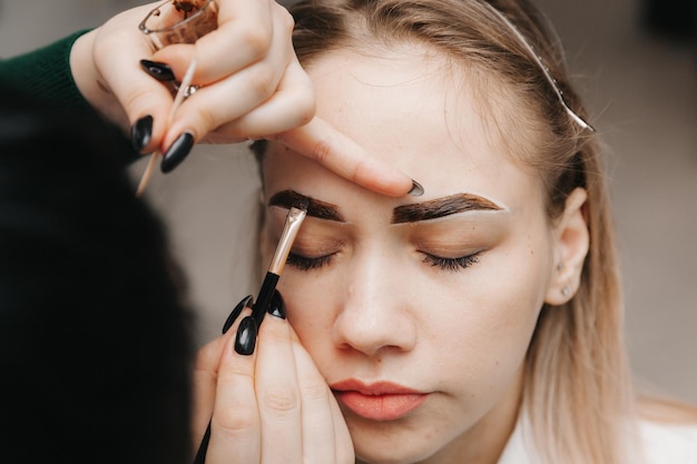 Une jeune femme subit une procédure de correction des sourcils dans un salon de beauté gros plan la fille peint ses sourcils dans le salon