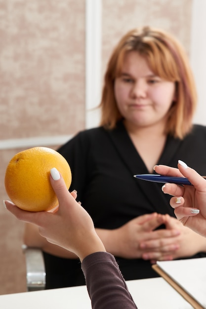 Jeune femme en surpoids visitant un nutritionniste pour perdre du poids avec l'aide d'un régime.