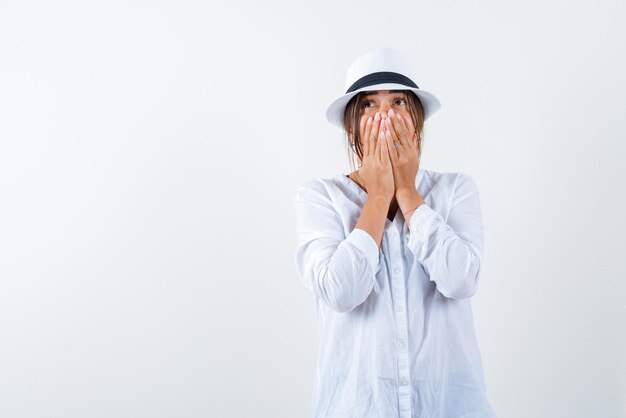 la jeune femme surprise couvre sa bouche avec les mains sur fond blanc