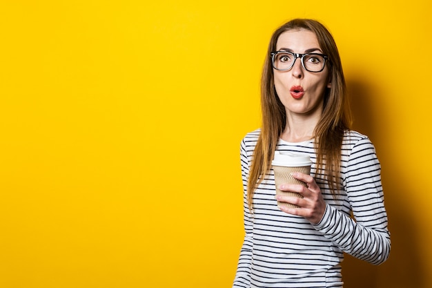 Jeune femme surprise dans des verres avec un café sur fond jaune