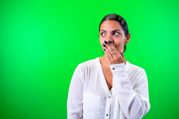 Jeune femme surprise la main sur la bouche fond vert