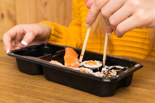 Jeune femme avec sushi sur fond de bois