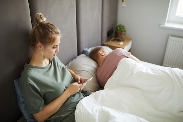 Jeune femme suspecte défilant dans son smartphone de mari