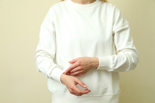 Jeune femme en sweat-shirt blanc sur fond beige