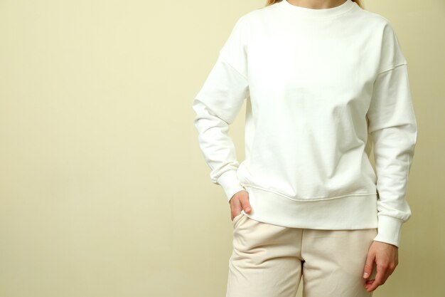 Jeune femme en sweat-shirt blanc sur fond beige