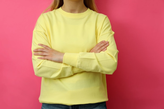 Jeune femme en sweat-shirt jaune sur fond rose