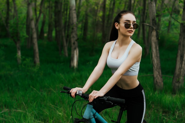 Jeune femme sympa a une balade à vélo dans un parc