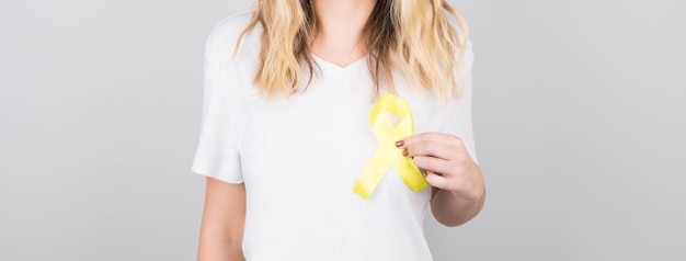 Jeune femme en t-shirt blanc tenant le symbole de sensibilisation du ruban jaune pour le suicide