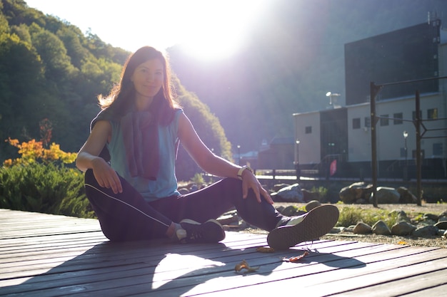 Une jeune femme avec un t-shirt bleu est assise sur un tapis roulant