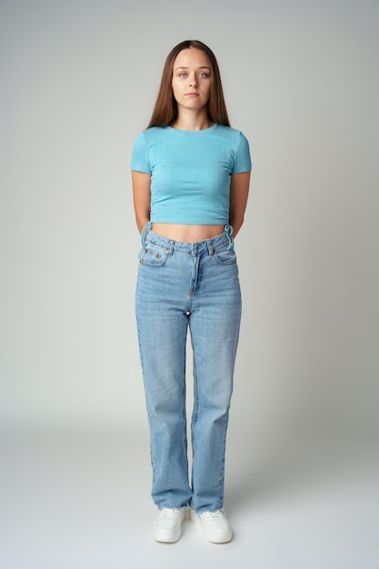 Une jeune femme en t-shirt bleu regarde la caméra avec une expression sérieuse.