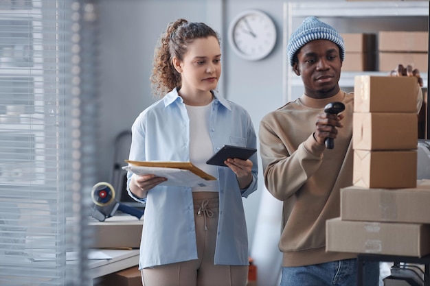 Jeune femme avec une tablette debout à côté d'un collègue masculin scannant des codes