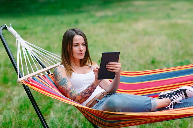 Jeune femme avec tablette sur le hamac