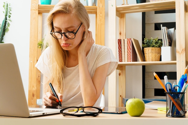 Jeune femme et tablette travaillant au bureau à domicile.