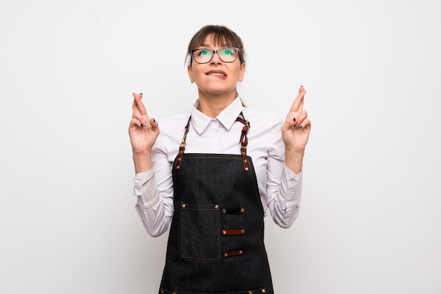 Jeune femme avec tablier avec les doigts qui se croisent et souhaitant le meilleur