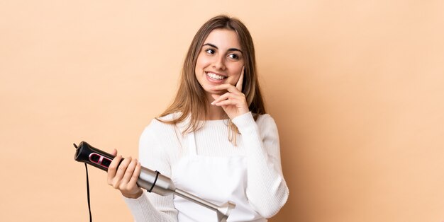 Jeune femme en tablier avec un mixeur