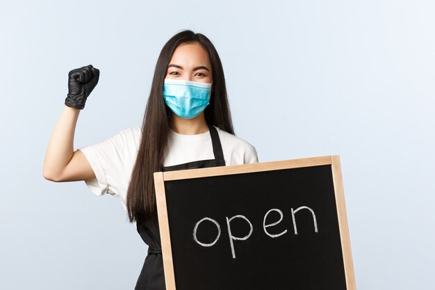 Jeune femme avec un tablier noir portant un masque médical