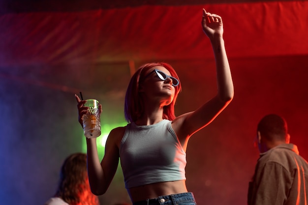 Une jeune femme de taille moyenne danse à une fête techno.